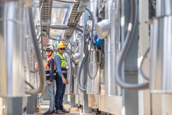 Portrait of HVAC engineer and technician wearing safety gear standing on a rooftop with urban buildings in the background, overseeing air conditioning system maintenance. Planing for CO2 reduction.
